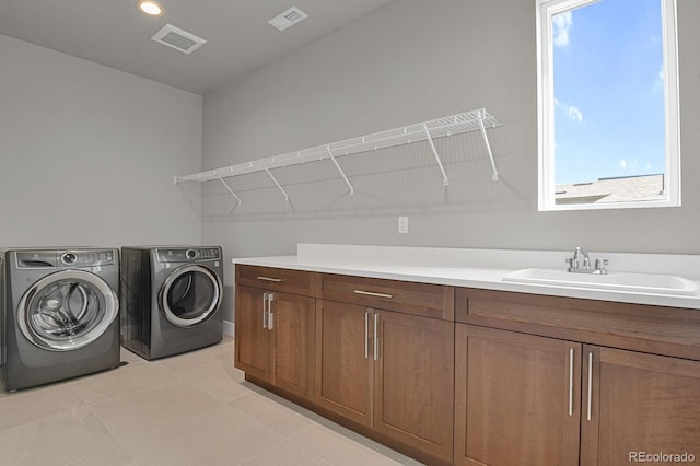 washroom featuring light tile patterned floors, washing machine and clothes dryer, cabinets, and sink