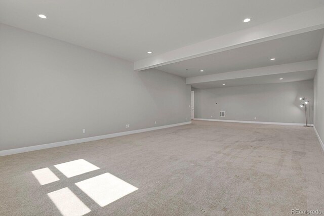 unfurnished room featuring light carpet and beam ceiling