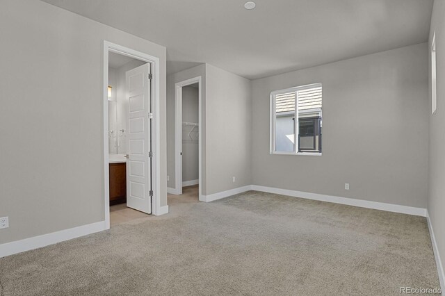 unfurnished bedroom featuring a closet, a spacious closet, and light carpet