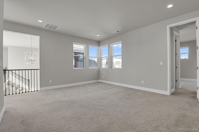 carpeted empty room with plenty of natural light and a chandelier