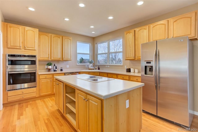 kitchen with light brown cabinetry, stainless steel appliances, and a center island