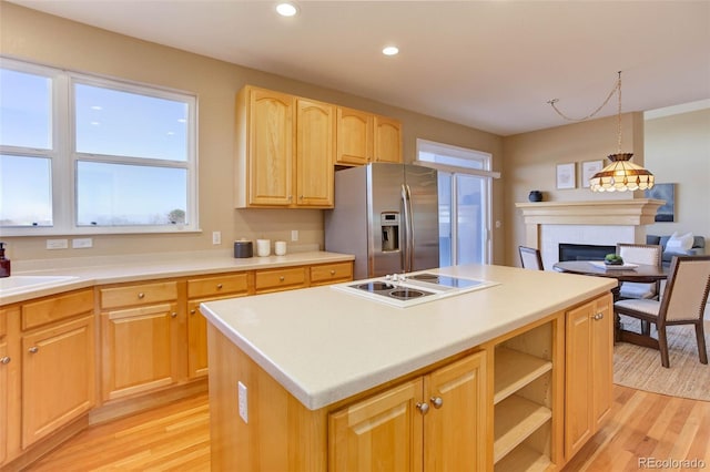 kitchen featuring stainless steel refrigerator with ice dispenser, a center island, hanging light fixtures, white electric stovetop, and a tile fireplace