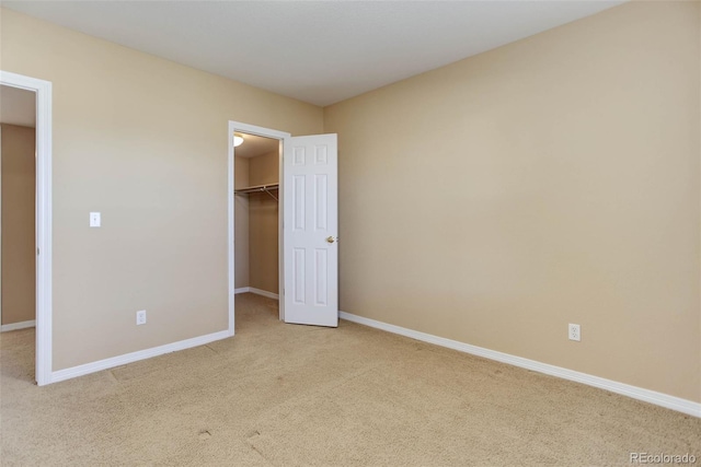 unfurnished bedroom with a spacious closet, light carpet, and a closet