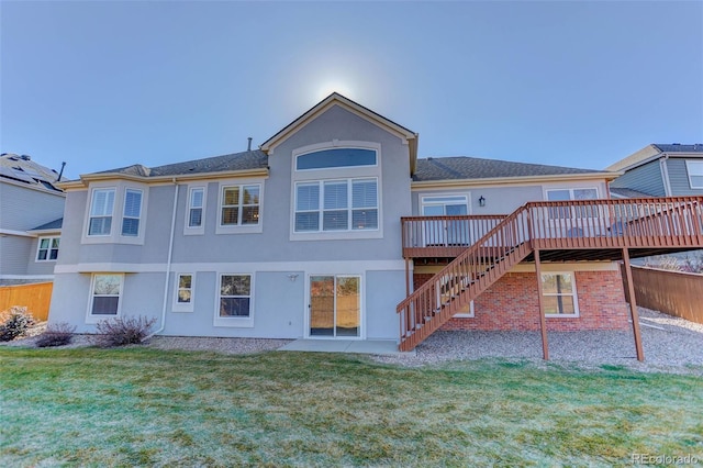 rear view of property featuring a wooden deck and a lawn