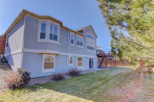 rear view of house featuring a wooden deck, cooling unit, and a lawn