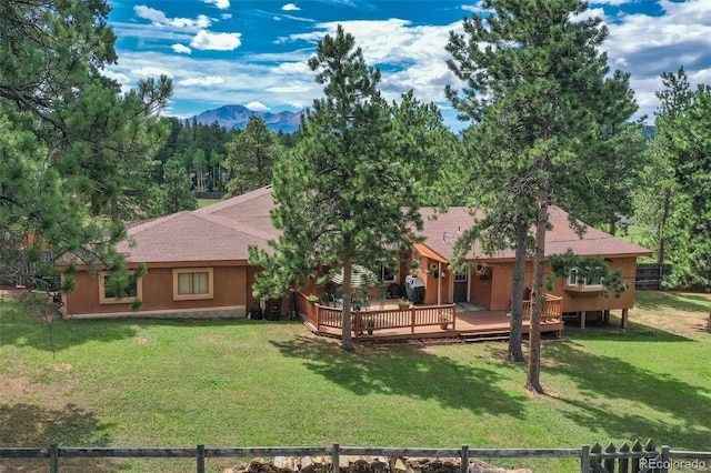 rear view of house with a lawn and a deck with mountain view