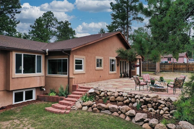 rear view of property with a patio, a yard, and a fire pit