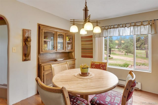 dining space with an inviting chandelier, light hardwood / wood-style flooring, and a baseboard radiator