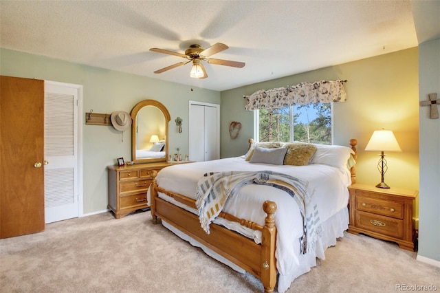 bedroom featuring ceiling fan, light colored carpet, a textured ceiling, and a closet