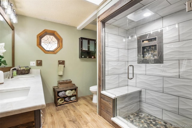 bathroom with hardwood / wood-style flooring, vanity, toilet, and a shower with shower door