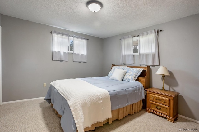 bedroom with multiple windows, a textured ceiling, and light carpet