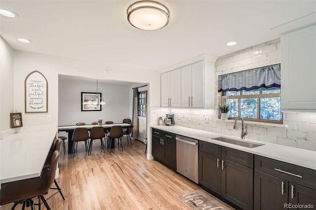 kitchen featuring pendant lighting, white cabinetry, tasteful backsplash, sink, and stainless steel dishwasher