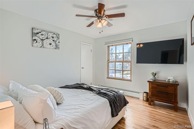 bedroom with ceiling fan, a baseboard heating unit, and light wood-type flooring