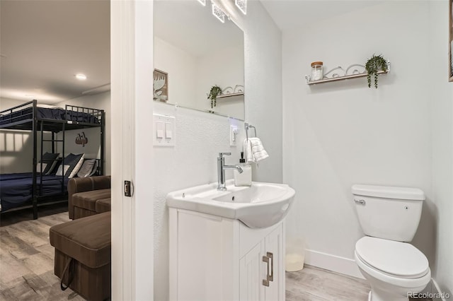 bathroom with hardwood / wood-style flooring, toilet, and vanity