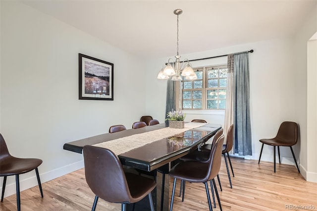 dining space featuring baseboards, light wood finished floors, and an inviting chandelier