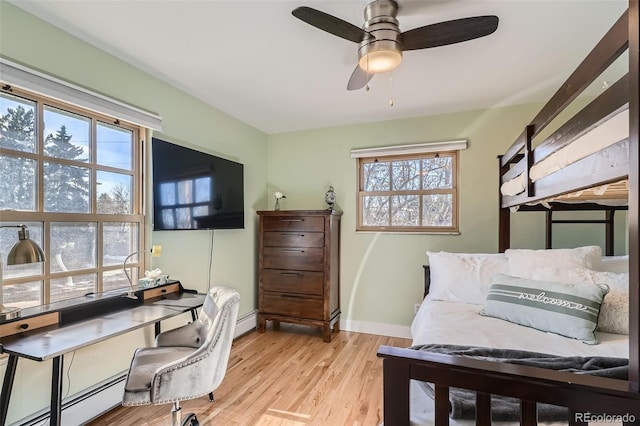 bedroom featuring a baseboard radiator, baseboards, and light wood finished floors