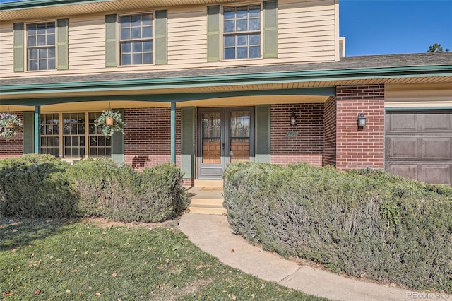 traditional-style home with french doors, brick siding, an attached garage, and a front yard