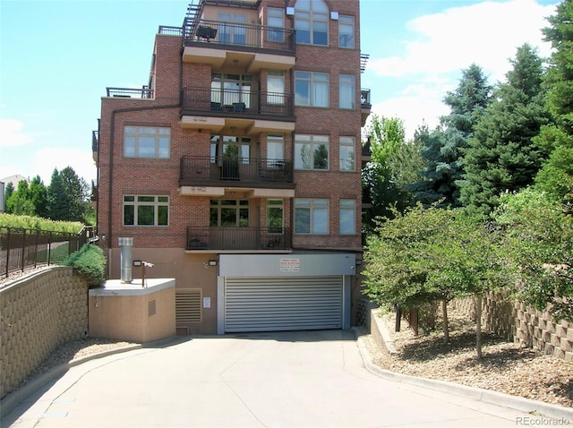 view of building exterior with an attached garage, fence, and concrete driveway