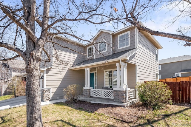 view of front of property featuring fence, covered porch, and roof with shingles