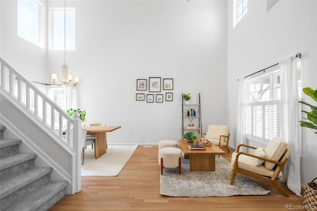 sitting room with a chandelier, stairs, light wood-style floors, and a healthy amount of sunlight