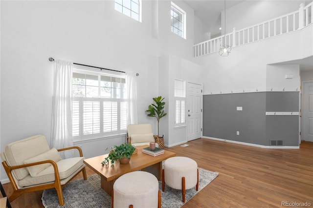 interior space featuring a towering ceiling, visible vents, baseboards, and wood finished floors