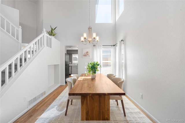 dining area featuring baseboards, a chandelier, stairway, light wood-style flooring, and visible vents