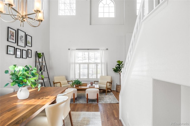 living area featuring stairway, dark wood-type flooring, a high ceiling, and an inviting chandelier