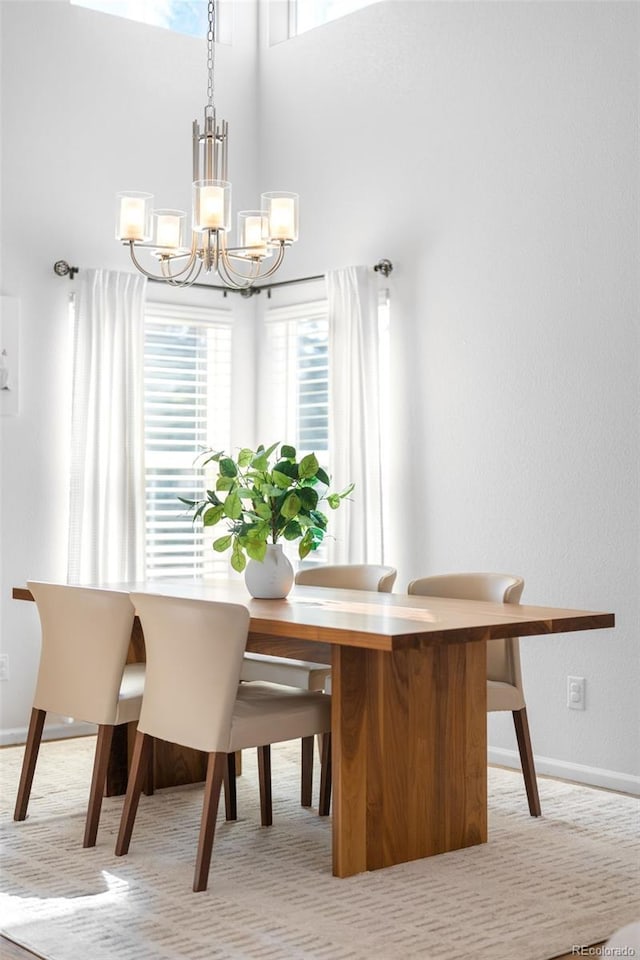 dining room featuring a chandelier, a towering ceiling, and baseboards
