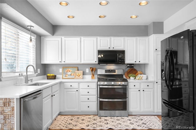 kitchen with light countertops, a sink, white cabinetry, and black appliances