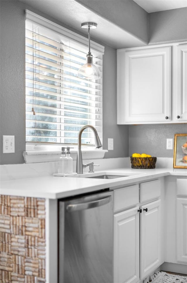 kitchen with light countertops, dishwasher, a sink, and white cabinetry
