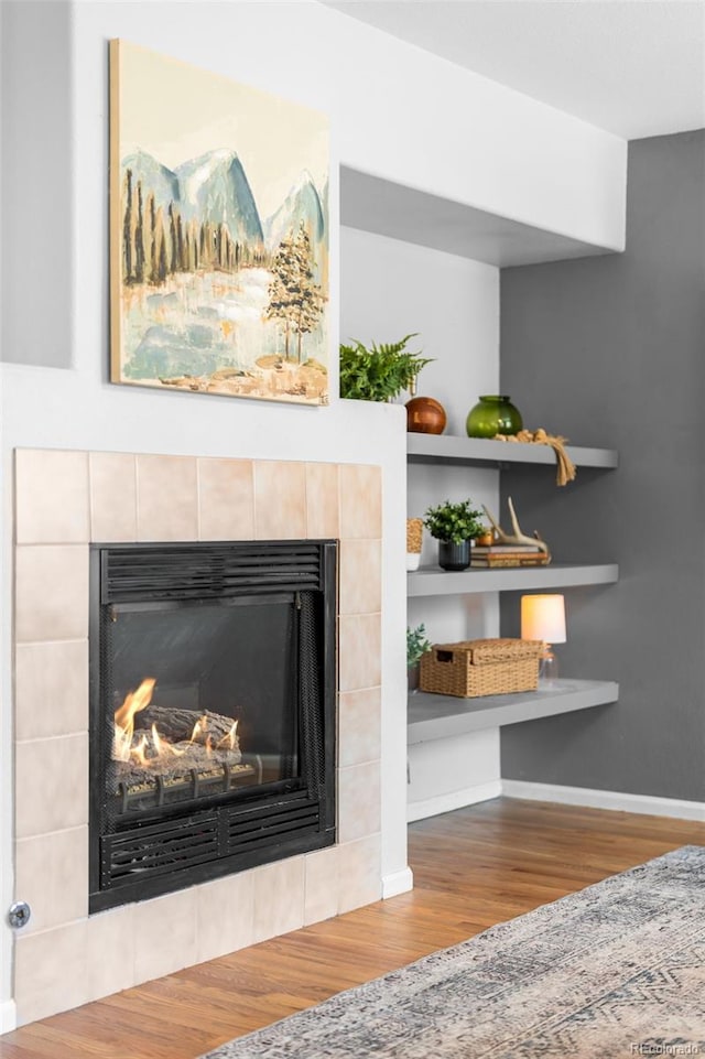 details featuring a fireplace, baseboards, built in features, and wood finished floors
