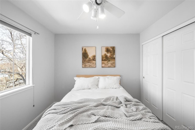 bedroom featuring a ceiling fan, a closet, baseboards, and multiple windows