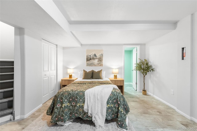 bedroom with beam ceiling, baseboards, and a closet