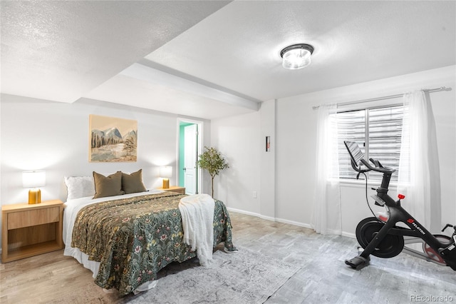 bedroom featuring a textured ceiling, baseboards, and wood finished floors