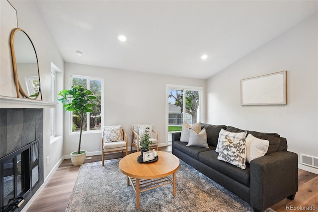 living room with lofted ceiling, plenty of natural light, hardwood / wood-style floors, and a fireplace