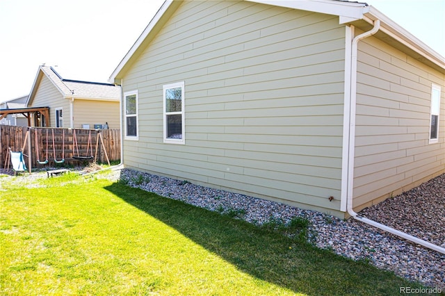 view of side of home featuring a yard and fence