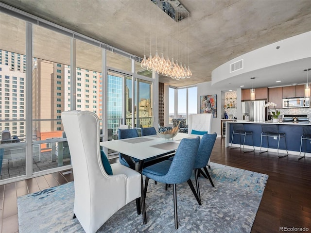dining space featuring a chandelier, expansive windows, visible vents, and hardwood / wood-style flooring