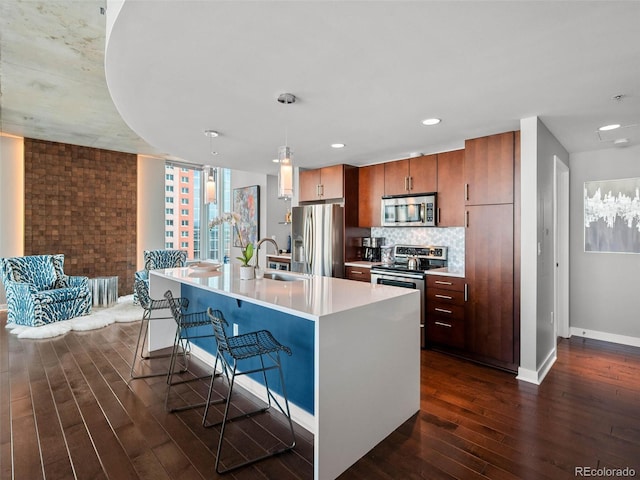 kitchen with baseboards, a sink, light countertops, appliances with stainless steel finishes, and dark wood finished floors