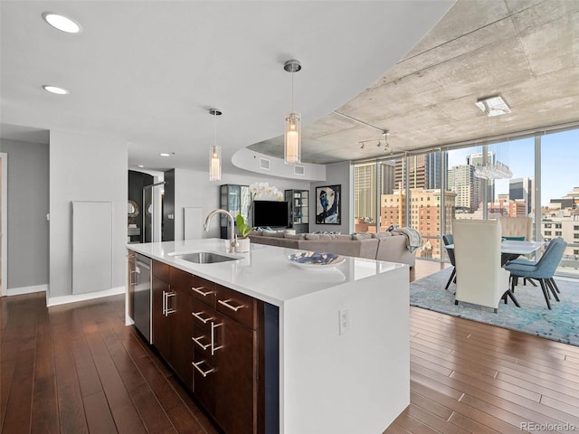 kitchen featuring decorative light fixtures, dark wood-style floors, light countertops, and a sink