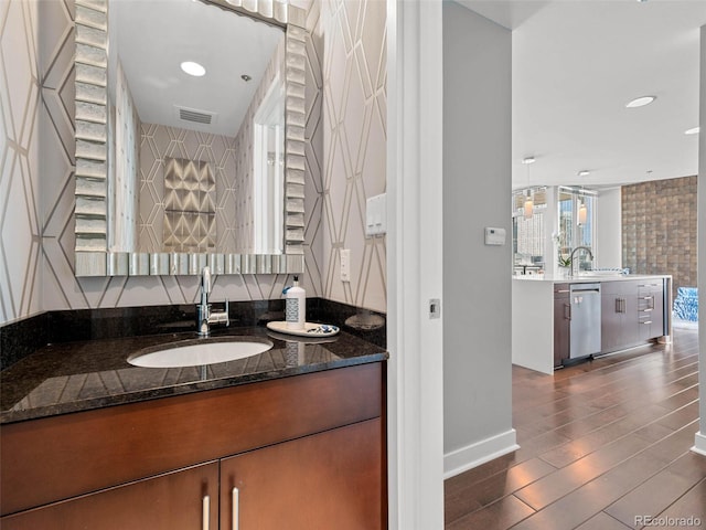 bathroom with two vanities, baseboards, visible vents, a sink, and wood finished floors