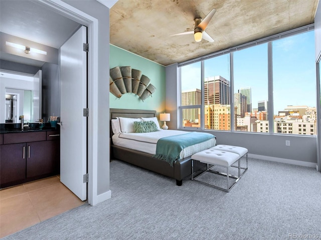 bedroom featuring a sink, baseboards, light carpet, and a city view