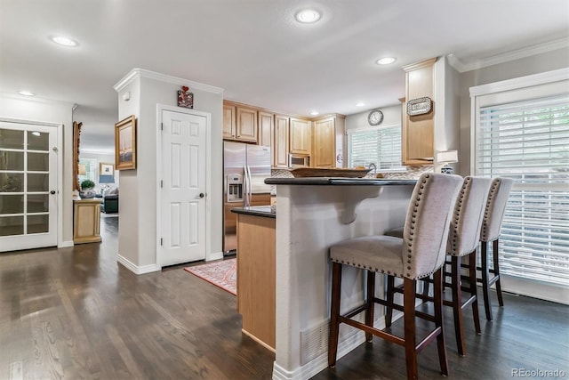 kitchen featuring ornamental molding, a kitchen bar, stainless steel fridge with ice dispenser, dark countertops, and dark wood finished floors