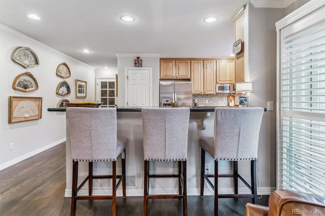 kitchen featuring dark wood-type flooring, stainless steel appliances, decorative backsplash, and a kitchen breakfast bar