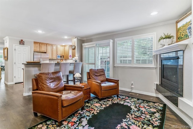 living area with a fireplace, baseboards, crown molding, and wood finished floors