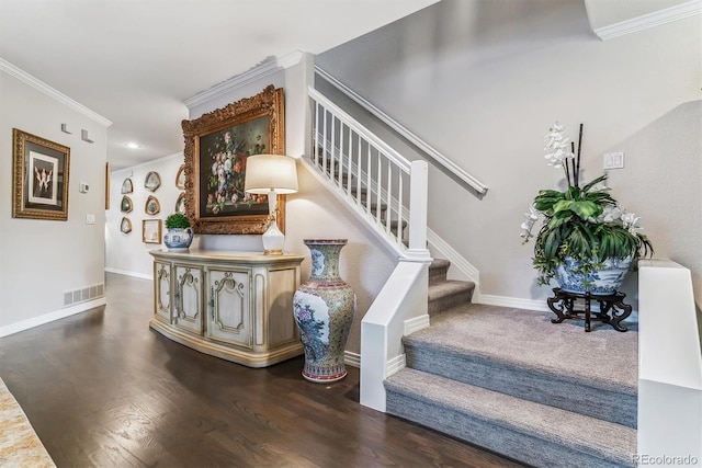 stairway with baseboards, wood finished floors, visible vents, and crown molding