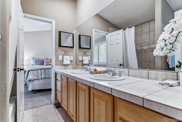 full bathroom with double vanity, curtained shower, tile patterned flooring, and a sink