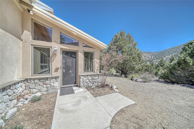 doorway to property featuring stone siding, stucco siding, and a mountain view