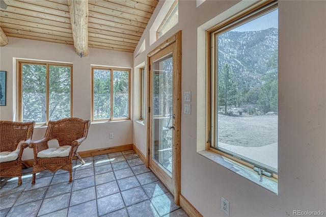 sunroom / solarium with a mountain view, vaulted ceiling with beams, baseboards, stone finish flooring, and wood ceiling