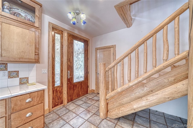 entrance foyer featuring baseboards, stone finish floor, and stairs