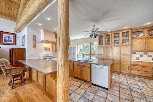 kitchen with a peninsula, a sink, white appliances, ceiling fan, and premium range hood